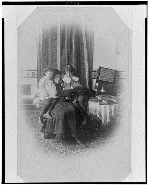 Marian Hubbard (1880–1962) und Elsie May Bell (1878-1964) mit Gouvernante, Schwarz-Weiß-Photographie, ca. 1885, unbekannter Photograph; Bildquelle: Library of Congress, Prints and Photographs Division Washington, Gilbert H. Grosvenor Collection of Photographs of the Alexander Graham Bell Family, Reproduction Number: LC-USZ62-122254, http://www.loc.gov/pictures/item/00649940/.