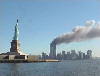 Skyline New Yorks am Morgen des Terroranschlags vom 11. Septembers 2001 mit den brennenden Zwillingstürmen des World Trade Centres; Bildquelle: National Park Service,  public domain; http://www.nps.gov/remembrance/statue/index 